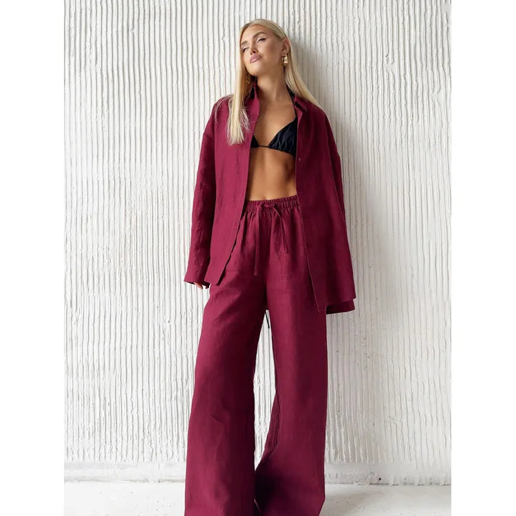Burgundy long sleeve fabric shirt and matching drawstring trousers worn over a black top against a white textured wall.