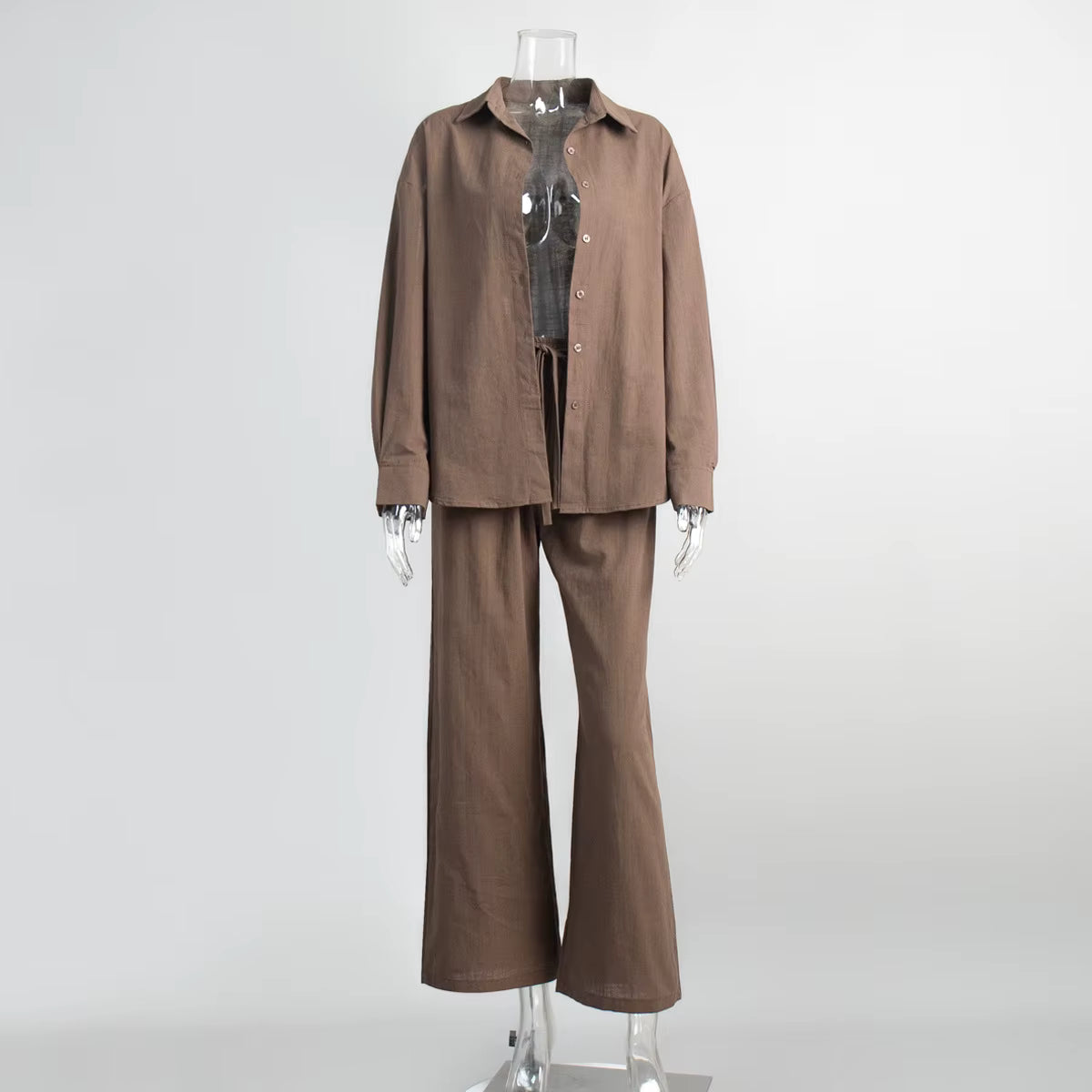 Brown fabric two-piece suit with a long-sleeve button-down shirt and drawstring trousers on a clear mannequin.