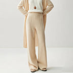Beige high-waisted wide leg knitted pants with a center seam, paired with a matching long cardigan and white top.