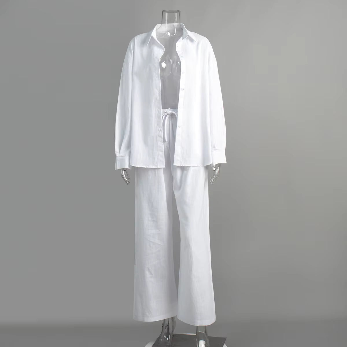 White long-sleeve button-down shirt and matching drawstring trousers on a clear mannequin.