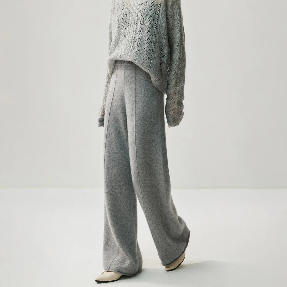 Grey knitted wide leg pants with a high waist and center seam detail, worn with a matching sweater and cream shoes.