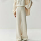Cream knitted wide leg pants with a high waist and center seam detail, worn with a matching sweater and cardigan.