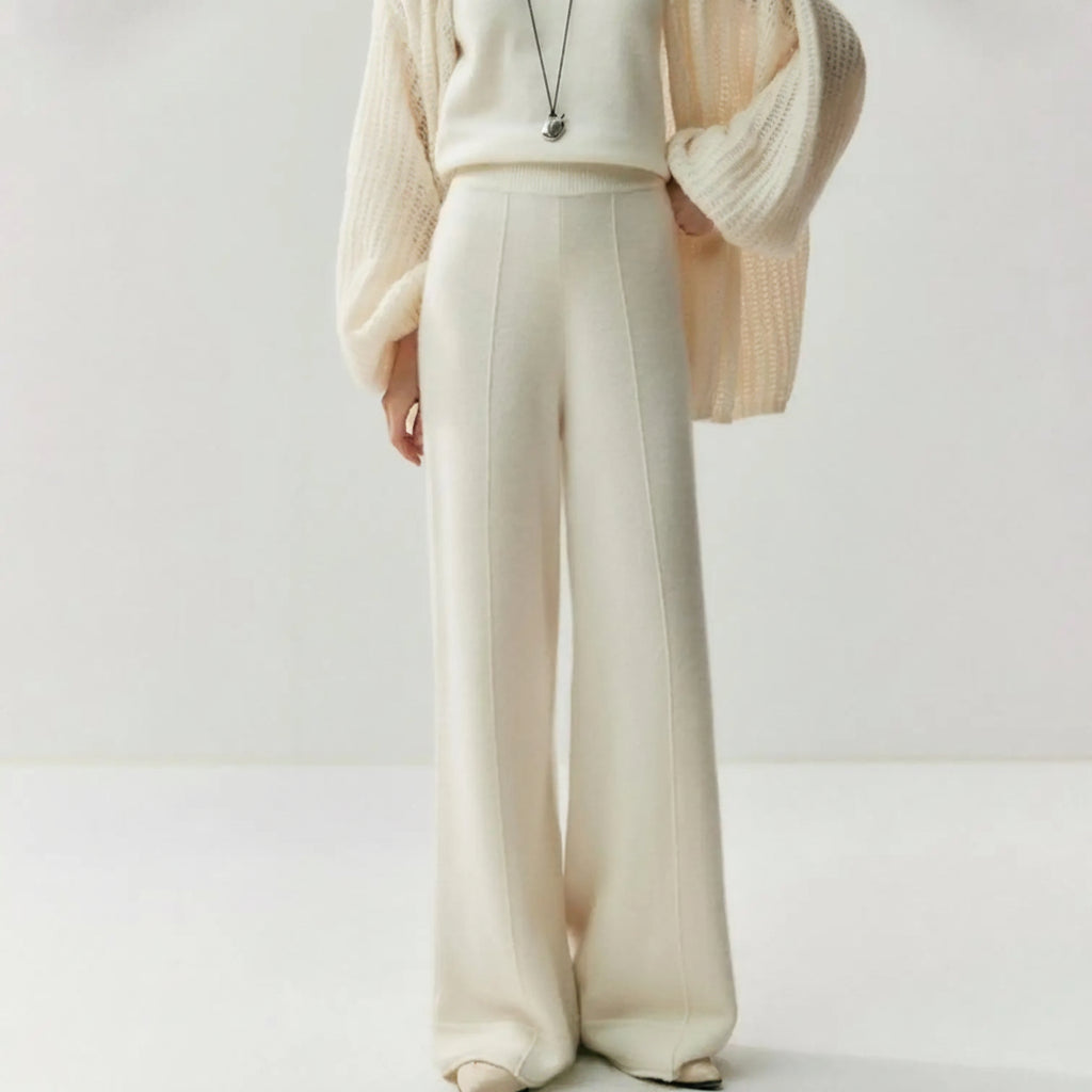 Cream knitted wide leg pants with a high waist and center seam detail, worn with a matching sweater and cardigan.