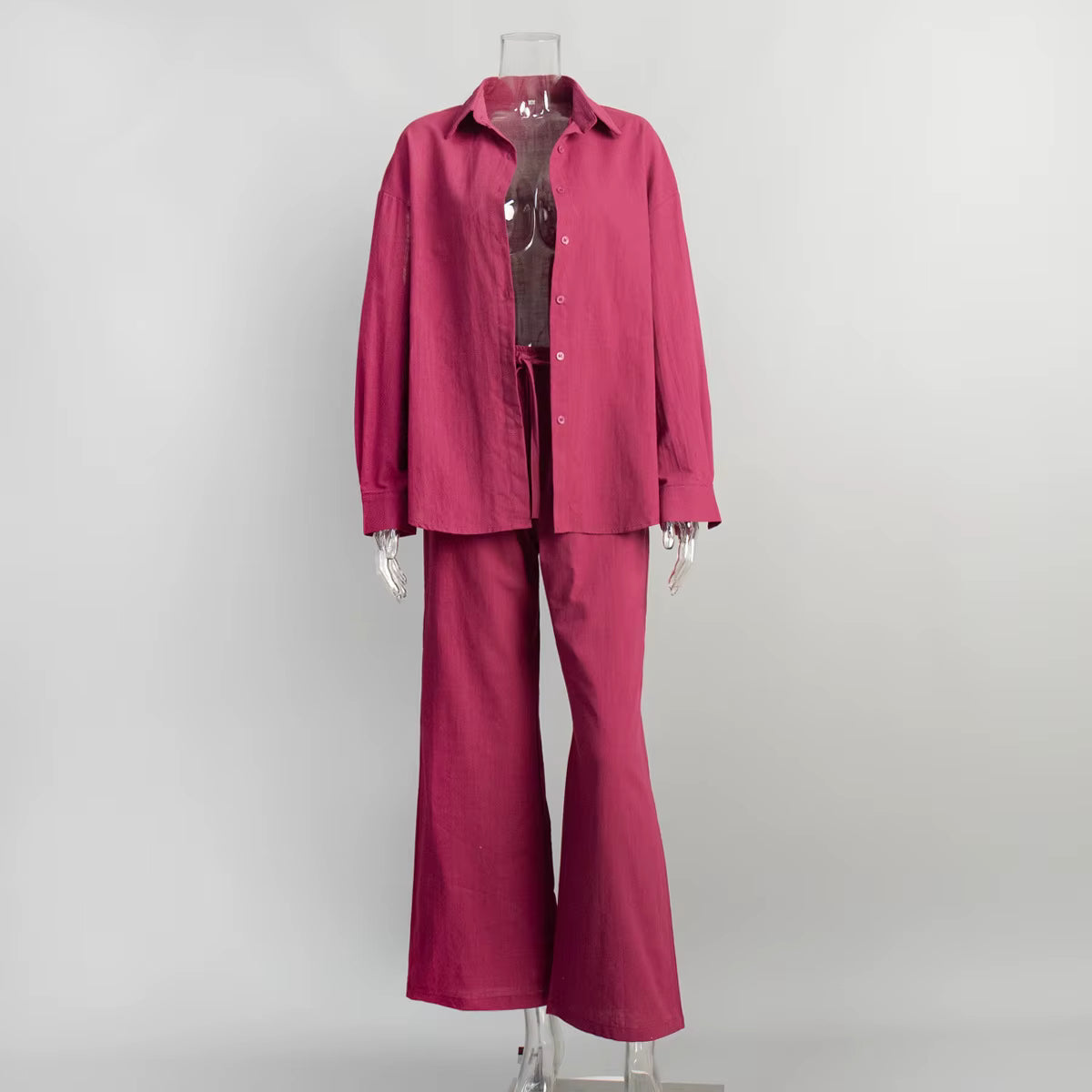 Magenta two-piece fabric suit with a long-sleeve button-down shirt and drawstring trousers on a clear mannequin.