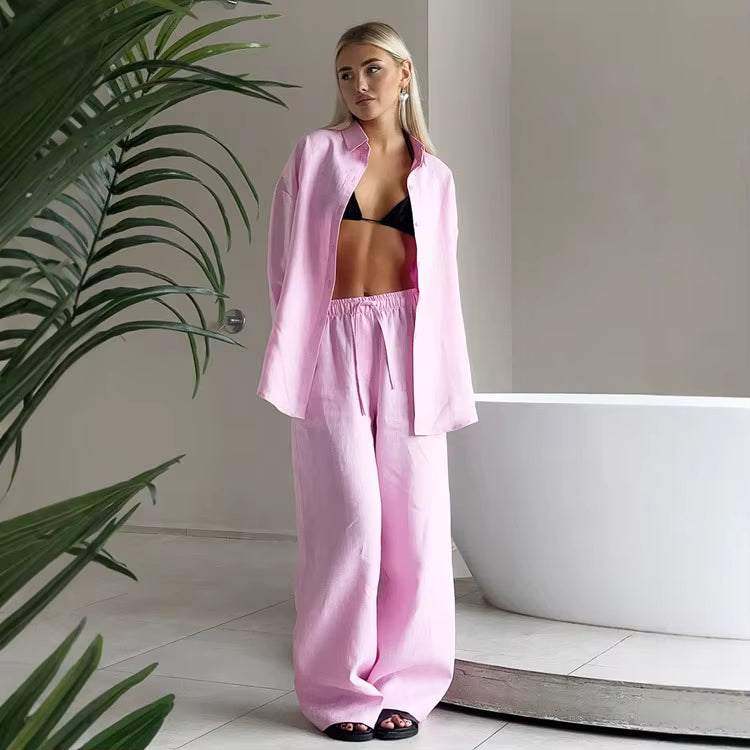 Pink long sleeve lapel shirt and matching drawstring trousers worn by a woman standing near a white bathtub.