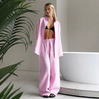 Pink long sleeve lapel shirt and matching drawstring trousers worn by a woman standing near a white bathtub.