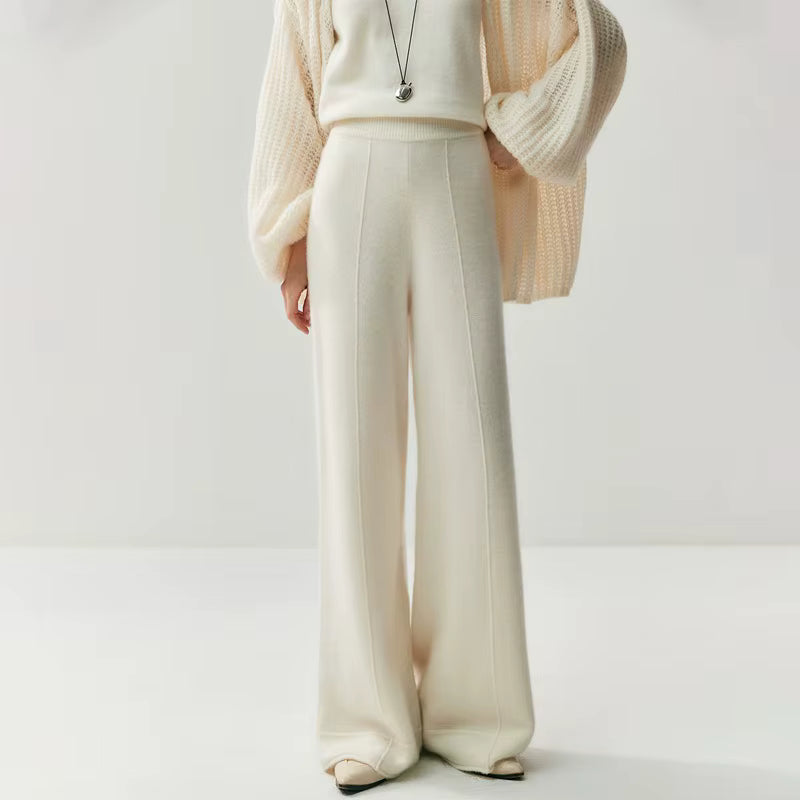 Cream white high-waisted wide leg knit pants with a vertical center seam, worn with a matching sweater and cardigan.