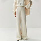 Cream white high-waisted wide leg knit pants with a vertical center seam, worn with a matching sweater and cardigan.